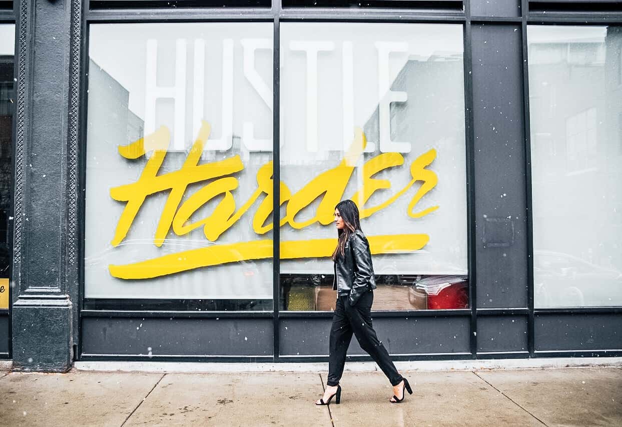 Career coach woman walking by "hustle" sign